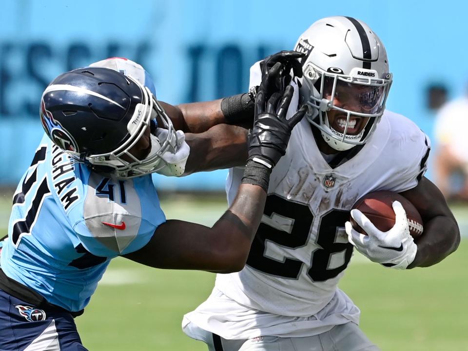 Josh Jacobs fights off a defender against the Tennessee Titans.