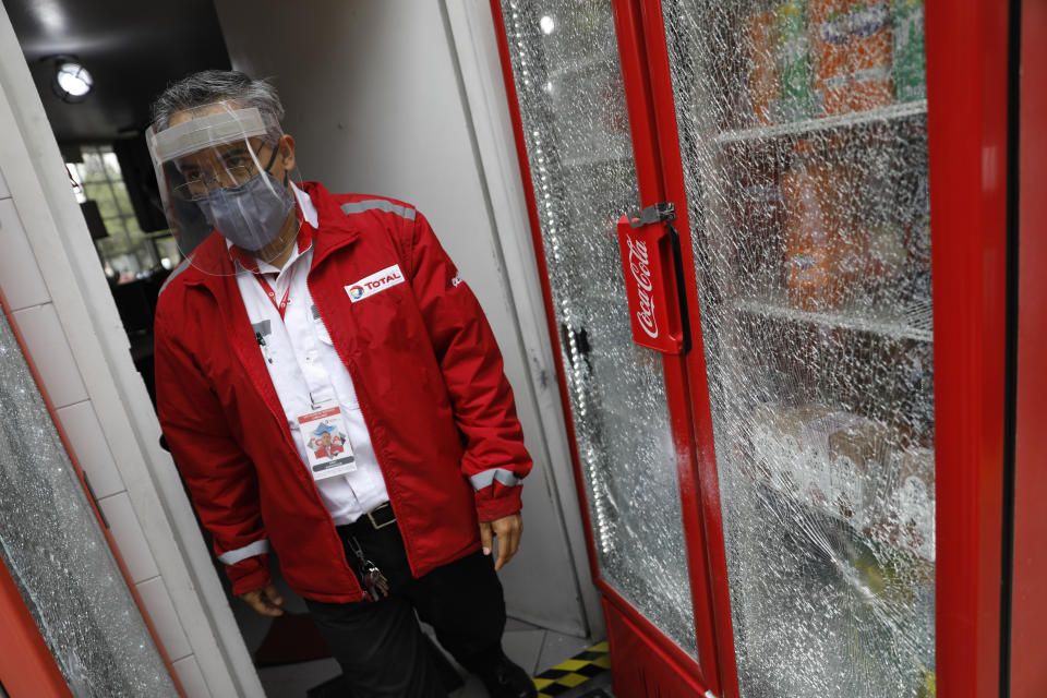 A gas station employee walks past drinks coolers that wereshattered during an attack by gunmen on police chief Omar Garcia Harfuch, in Mexico City, Friday, June 26, 2020. Heavily armed gunmen attacked and wounded Mexico City's police chief in an operation that left several dead. (AP Photo/Rebecca Blackwell)