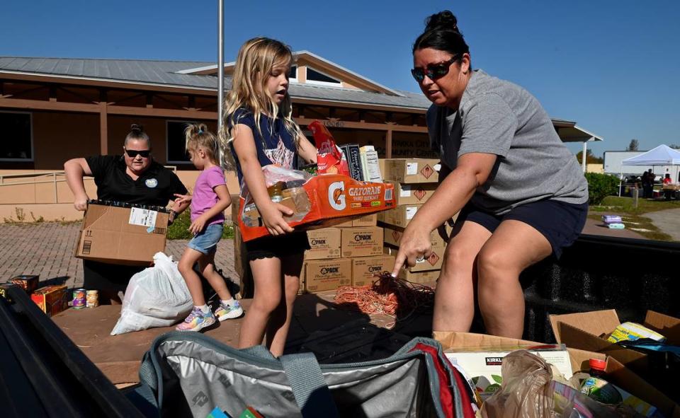 Tia Bigi, right, points where she would like her daughter, Bailey, 6, to set supplies in the bed of her truck as Bigi and her daughters gather supplies for families impacted by Hurricane Ian at the Myakka Community Center October 7, 2022.