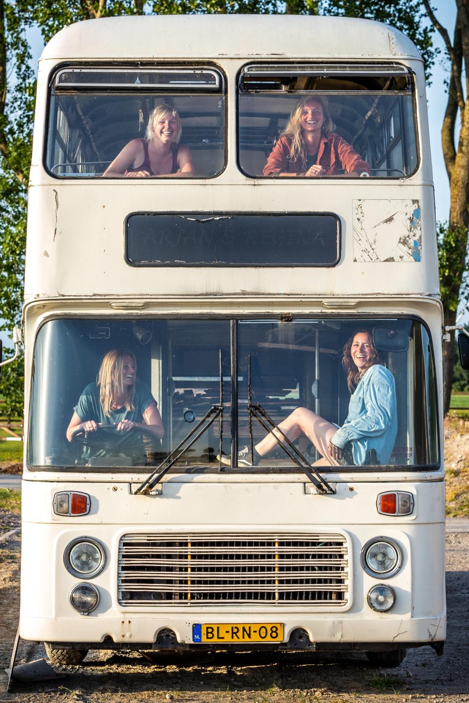 The four women sitting in the front windows of the double decker bus