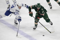 Toronto Maple Leafs center Auston Matthews (34) and Minnesota Wild left wing Marcus Foligno (17) battle for the puck during the first period of an NHL hockey game, Saturday, Dec. 4, 2021, in St. Paul, Minn. (AP Photo/Andy Clayton-King)