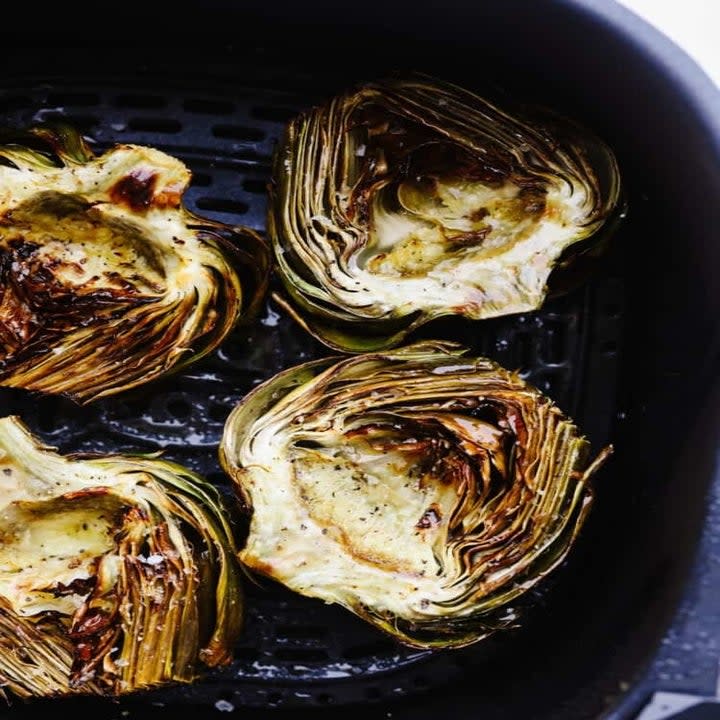 Artichokes in an air fryer basket.