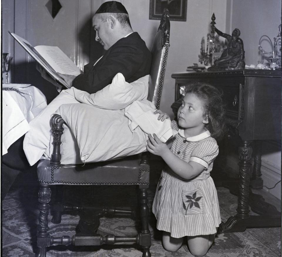 A young girl pretends she is 'stealing' the bread, Afikomen, as part of Passover celebrations.