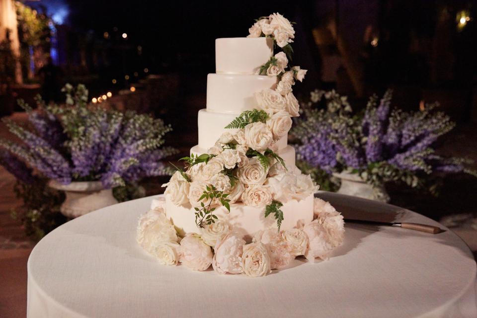 After dinner, guests regrouped in the square where the ceremony had taken place to watch the bride and groom cut their four-layer cake covered in white roses by Wedding Cakes in Tuscany.