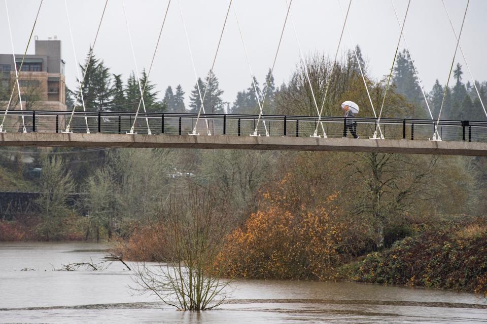 A walker goes across the Peter Courtney Minto Island Bridge during the rain on Wednesday, Dec. 6, 2023, in Salem, Ore.