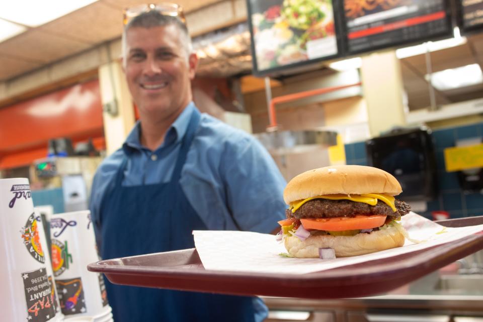 The Pad owner Troy Mentzer serves up a deluxe burger Friday afternoon with all the fixings.