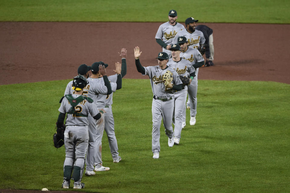 Oakland Athletics' Ramon Laureano, center facing camera, and the rest of the team celebrate a 7-2 win over the Baltimore Orioles in a baseball game Saturday, April 24, 2021, in Baltimore. (AP Photo/Gail Burton)