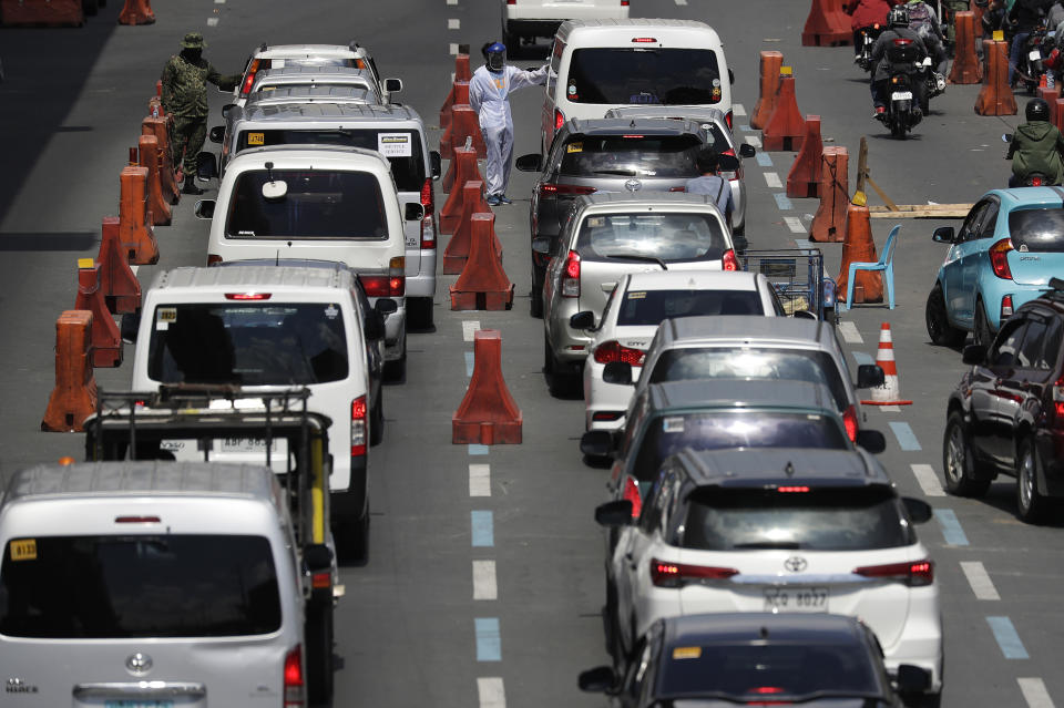 Police officers check temperatures and identities of motorists at a checkpoint outside Manila, Philippines, Monday, May 18, 2020. Crowds and vehicular traffic returned to shopping malls in the Philippine capital after a two-month coronavirus lockdown was partially relaxed over the weekend, prompting police to warn of arrests and store closures. (AP Photo/Aaron Favila)