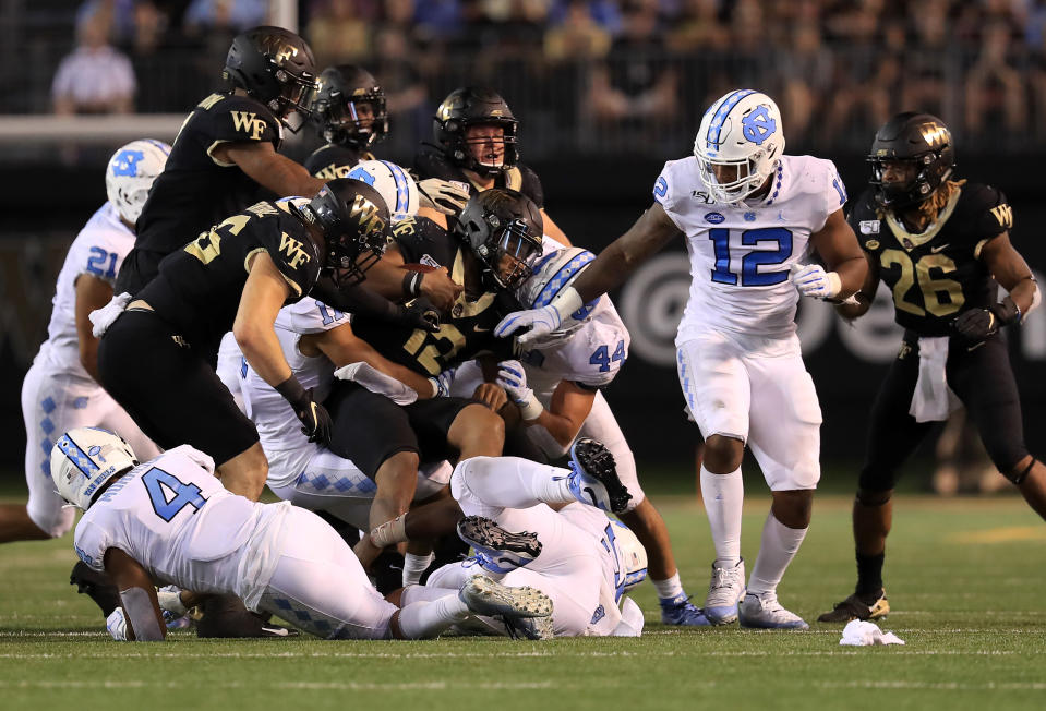 WINSTON SALEM, NORTH CAROLINA - SEPTEMBER 13: Jamie Newman #12 of the Wake Forest Demon Deacons is tackled by the defense of the North Carolina Tar Heels during their game at BB&T Field on September 13, 2019 in Winston Salem, North Carolina. (Photo by Streeter Lecka/Getty Images)