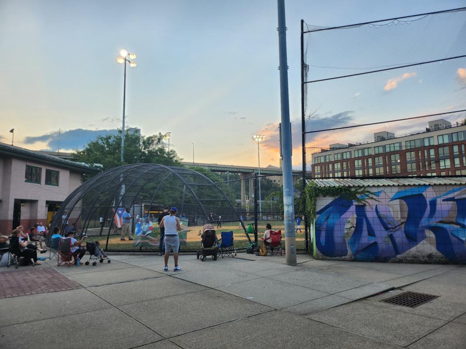 <p>A picture taken with the Galaxy Z Flip 4 showing a group of people outside a baseball pitch at sunset.</p>
