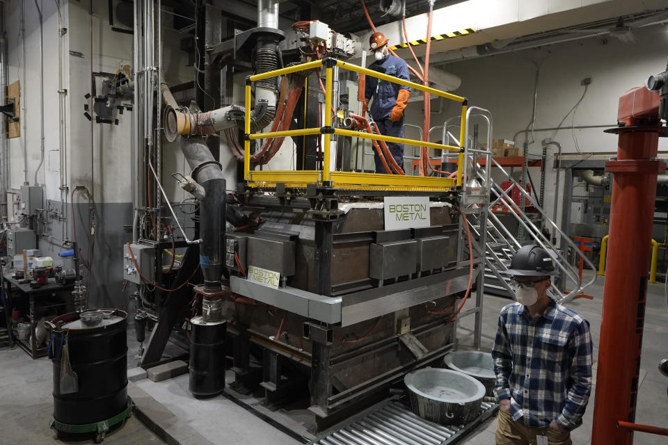 A worker, below right, walks past a machine known as an electrolytic cell, center, that uses electric current to produce liquid iron, at Boston Metal, Wednesday, Jan. 25, 2023, in Woburn, Mass. The manufacture of ‘green steel’ moved one step closer to reality Friday, Jan. 27, as Boston Metal announced a $120 million investment from the world's second-largest steelmaker, ArcelorMittal. (AP Photo/Steven Senne)