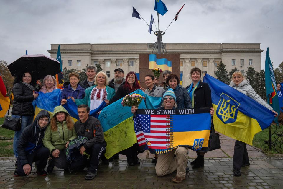 People hold national flags and pose for a photo as the city marks one year since Ukraine retook the city of Kherson from occupying Russian forces, in central square in Kherson (AP)