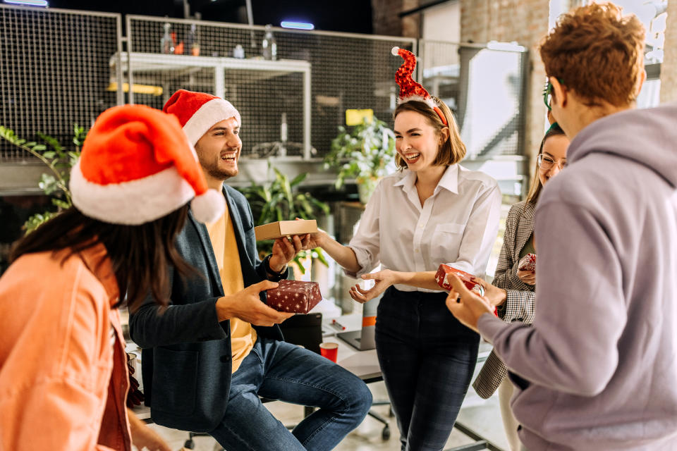 Coworkers handing each other gifts in the office