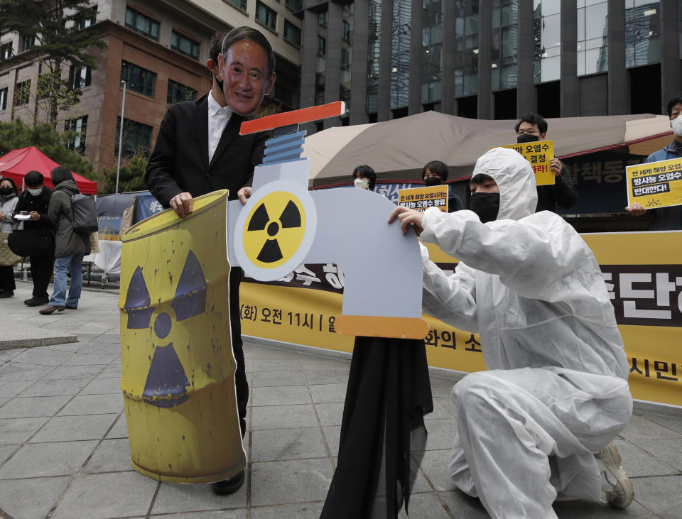 An environmental activist wearing a mask of Japanese Prime Minister Yoshihide Suga performs to denounce the Japanese government's decision on Fukushima water, near the Japanese embassy in Seoul, South Korea, Tuesday, April 13, 2021. Japan's government decided Tuesday to start releasing massive amounts of treated radioactive water from the wrecked Fukushima nuclear plant into the Pacific Ocean in two years - an option fiercely opposed by local fishermen and residents. (AP Photo/Lee Jin-man)