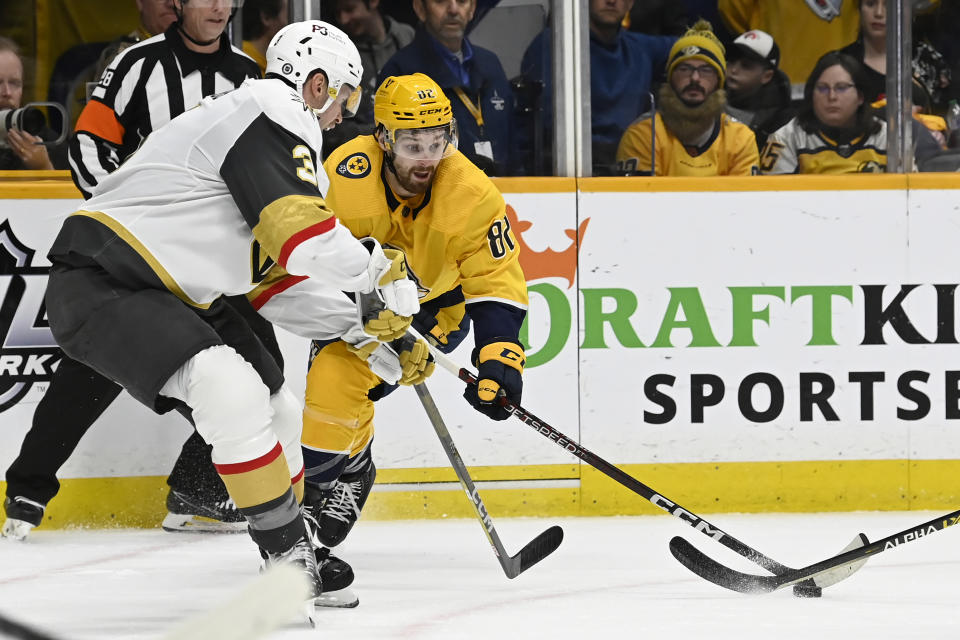 Nashville Predators center Tommy Novak (82) reaches for the puck as Vegas Golden Knights defenseman Brayden McNabb (3) defends during the second period of an NHL hockey game Tuesday, Feb. 7, 2023, in Nashville, Tenn. (AP Photo/Mark Zaleski)