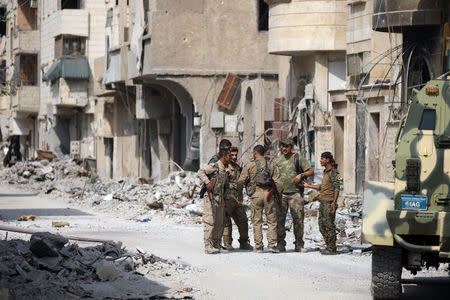 Fighters from Syrian Democratic Forces (SDF) stand together along a damaged street in Raqqa, Syria September 16, 2017. REUTERS/ Rodi Said