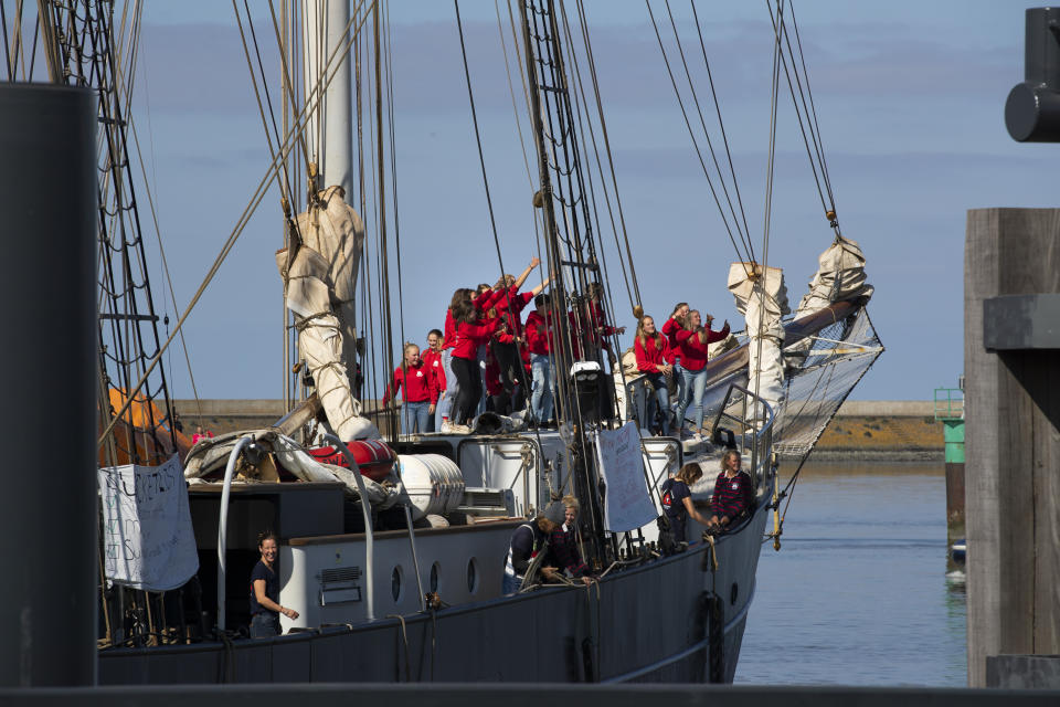 Dutch teens cheer on their schooner after sailing home from the Caribbean across the Atlantic when coronavirus lockdowns prevented them flying, in the port of Harlingen, northern Netherlands, Sunday, April 26, 2020. (AP Photo/Peter Dejong)