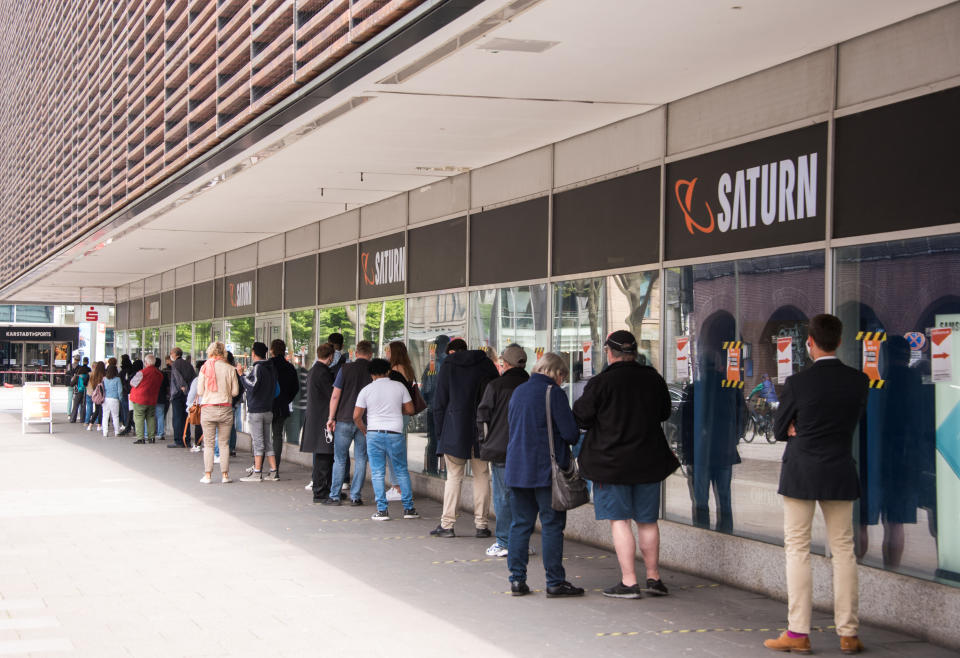 Hamburg: Kunden stehen in einer langen Schlange vor dem Elektromarkt «Saturn» und warten auf den Einlass. Foto: Daniel Bockwoldt / dpa