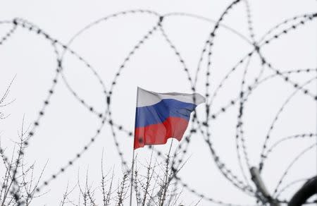 The Russian flag is seen through barbed wire as it flies on the roof of the Russian embassy in Kiev, Ukraine March 26, 2018. REUTERS/Gleb Garanich/Files