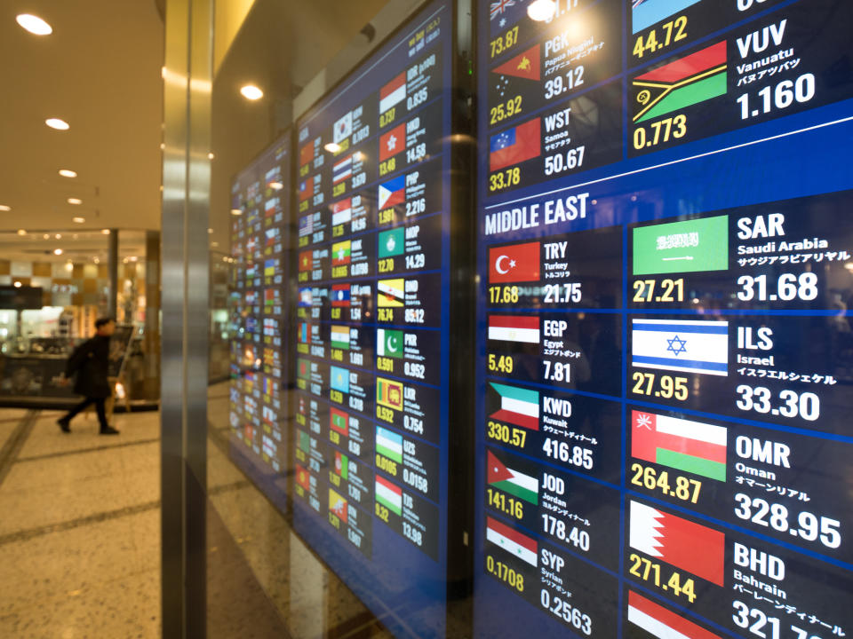 A colorful digital currency board displays exchange rates for international currencies.