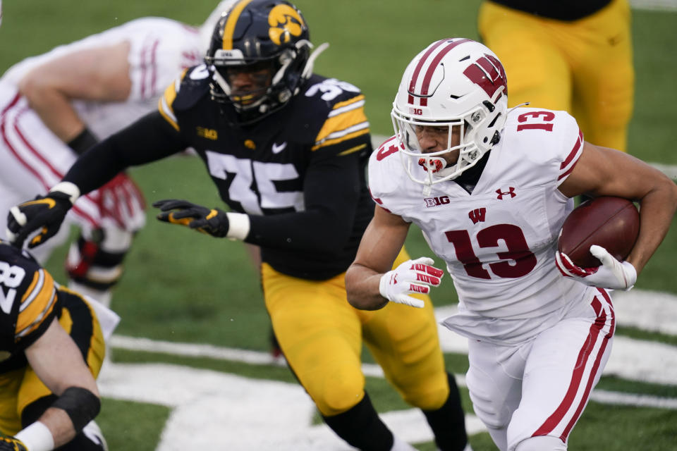 Wisconsin wide receiver Chimere Dike (13) runs from Iowa linebacker Barrington Wade (35) during the first half of an NCAA college football game, Saturday, Dec. 12, 2020, in Iowa City, Iowa. (AP Photo/Charlie Neibergall)