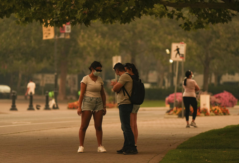 People wear masks due to poor air quality as smoke from the McDougall Creek wildfire fills the air in Kelowna, British Columbia, Friday, Aug. 18, 2023. (Darryl Dyck/The Canadian Press via AP)