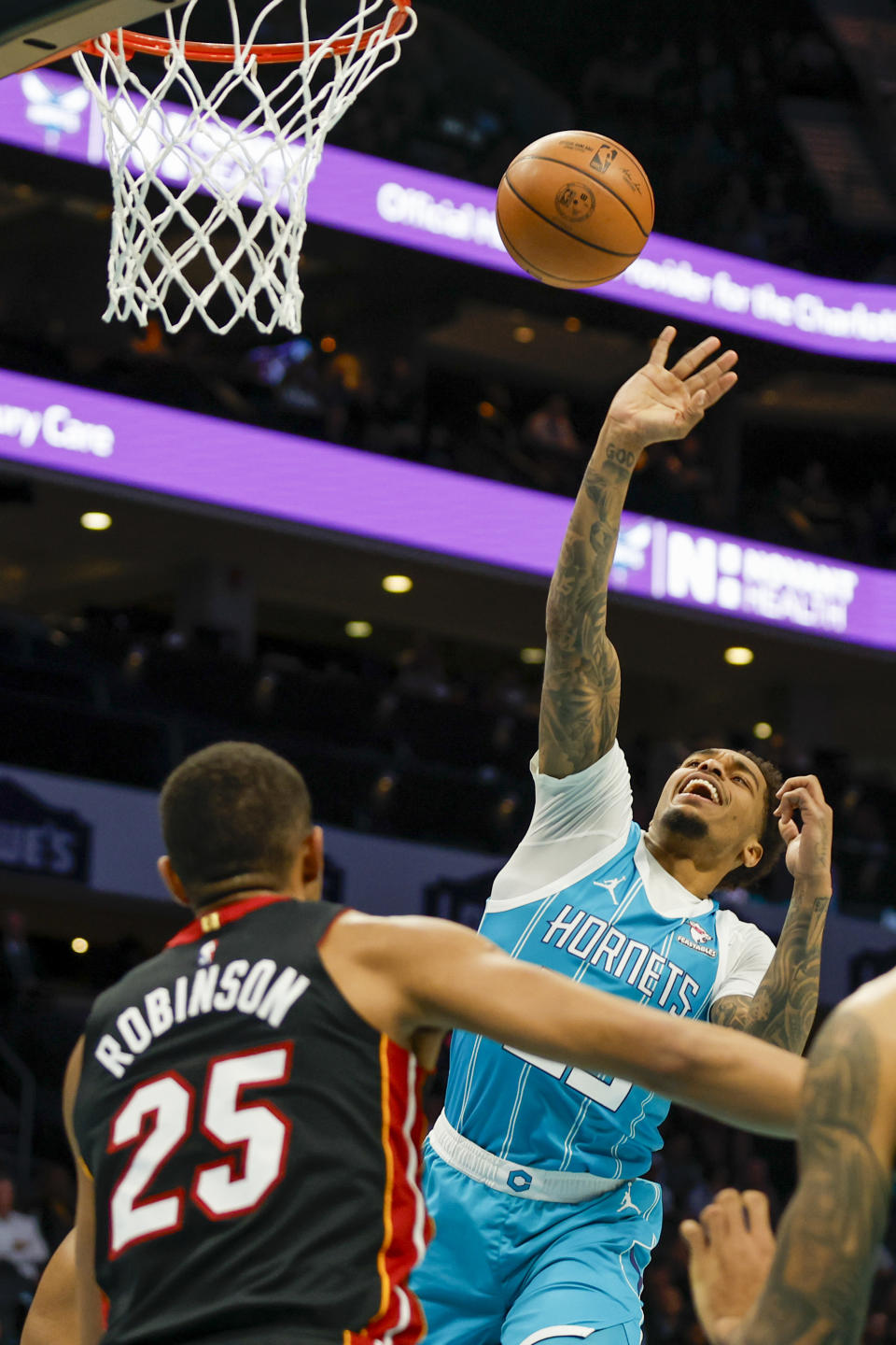 Charlotte Hornets forward P.J. Washington, right, shoots over Miami Heat center Orlando Robinson (25) during the first half of an NBA basketball game in Charlotte, N.C., Monday, Dec. 11, 2023. (AP Photo/Nell Redmond)