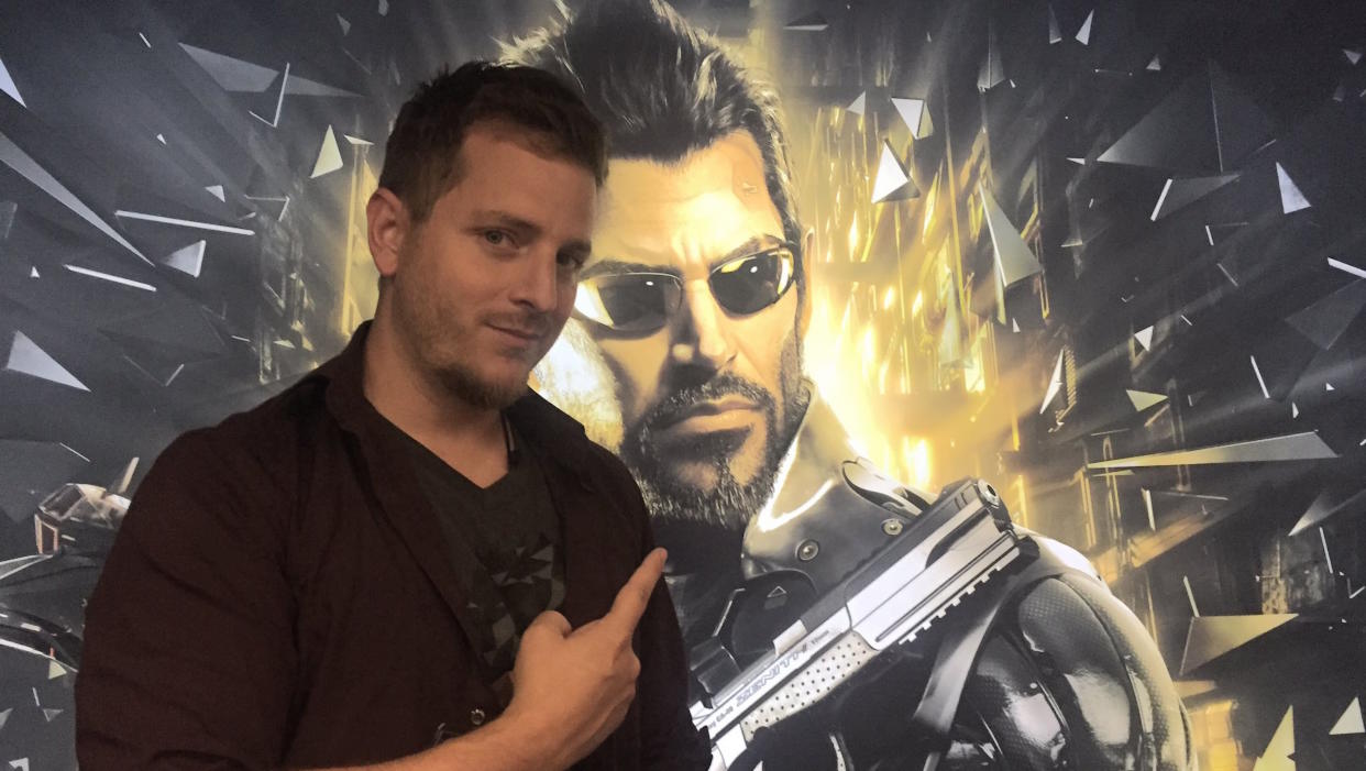  Elias Toufexis pointing at a picture of Adam Jensen. 