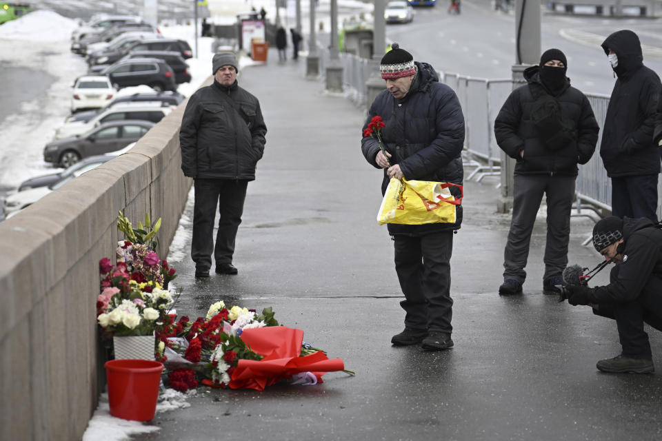 A man lays flowers at the place where Russian opposition leader Boris Nemtsov was gunned in 2015, as he comes to mark the 9th anniversary of his killing in Moscow, Russia, Tuesday, Feb. 27, 2024. (AP Photo)