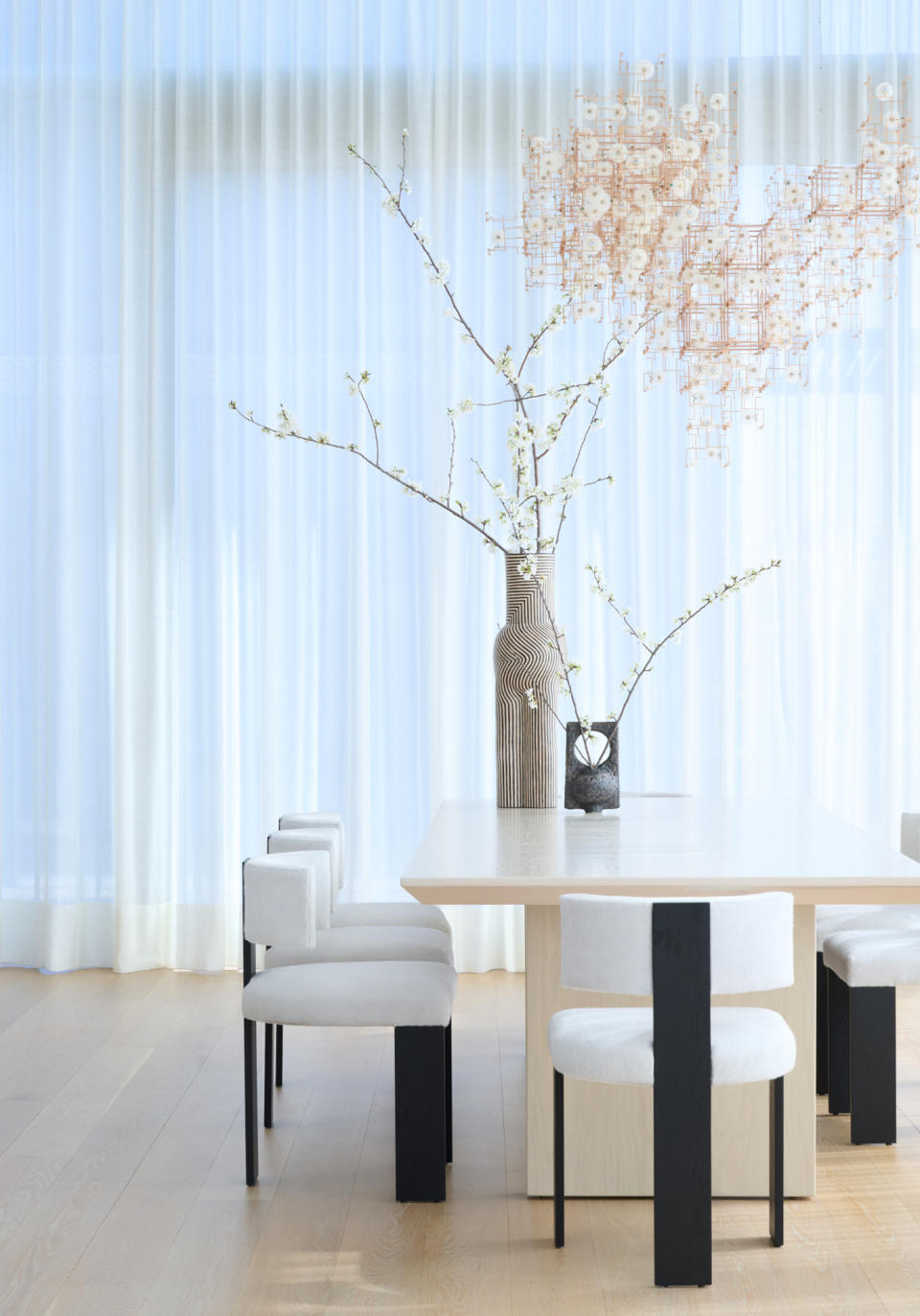 Dining area with square block travertine table and black and white dining chairs