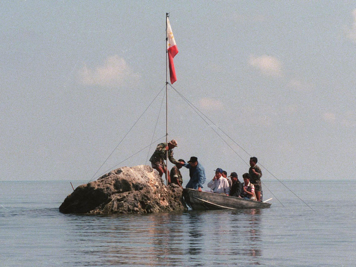 A team of navy personnel and three Philippine congressmen standing on a tiny rock in the Scarborough Shoal with a Filipino flag in protest at Chinese land grabbing: AFP/Getty Images