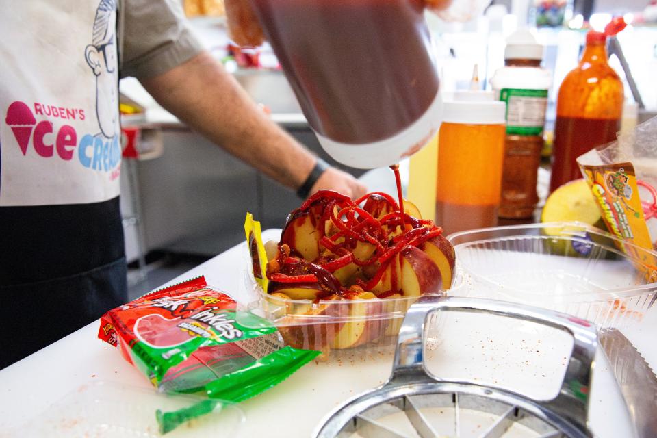 Jesus Fuentes adds chamoy to manzanas locas at Ruben's Ice Cream y Antojitos Mexicanos on Thursday, March 21, 2024, in Keizer, Ore.