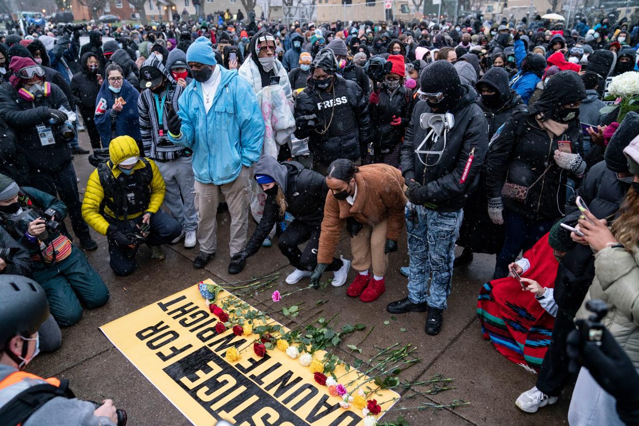 Flowers are placed on a banner as demonstrators gather outside the Brooklyn Center Police Department on Tuesday, April 13, 2021, to protest the shooting death of Daunte Wright on Sunday during a traffic stop in Brooklyn Center, Minn.