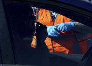 FILE - A patient takes a nasal swab for their COVID-19 Polymerase Chain Reaction (PCR) test while a worker watches during the Federal Emergency Management Agency's drive-through COVID-19 testing site at Pima Community College West Campus in Tucson, Ariz. on Monday, Jan. 24, 2022. Omicron, the highly contagious coronavirus variant sweeping across the country, is driving the daily American death toll higher than during last fall's delta wave, with deaths likely to keep rising for days or even weeks. (Rebecca Sasnett/Arizona Daily Star via AP)