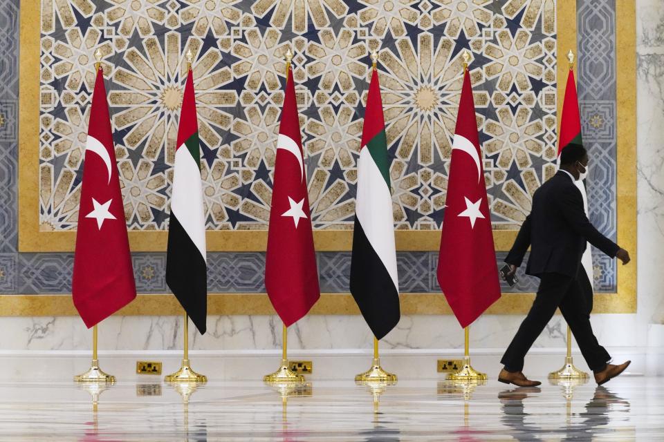 An official walks past Turkish and Emirati flags at Qasr Al-Watan in Abu Dhabi, United Arab Emirates, Monday, Feb. 14, 2022. Turkish President Recep Tayyip Erdogan traveled Monday to the United Arab Emirates, a trip signaling a further thaw in relations strained over the two nations' approaches to Islamists in the wake of the 2011 Arab Spring. (AP Photo/Jon Gambrell)