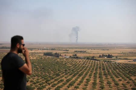 Man looks on as smoke rises near the Syrian town of Ras al-Ain as seen from the Turkish border town of Ceylanpinar