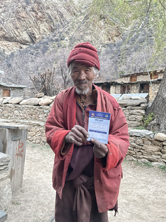 An elderly man holds up a vaccine card.