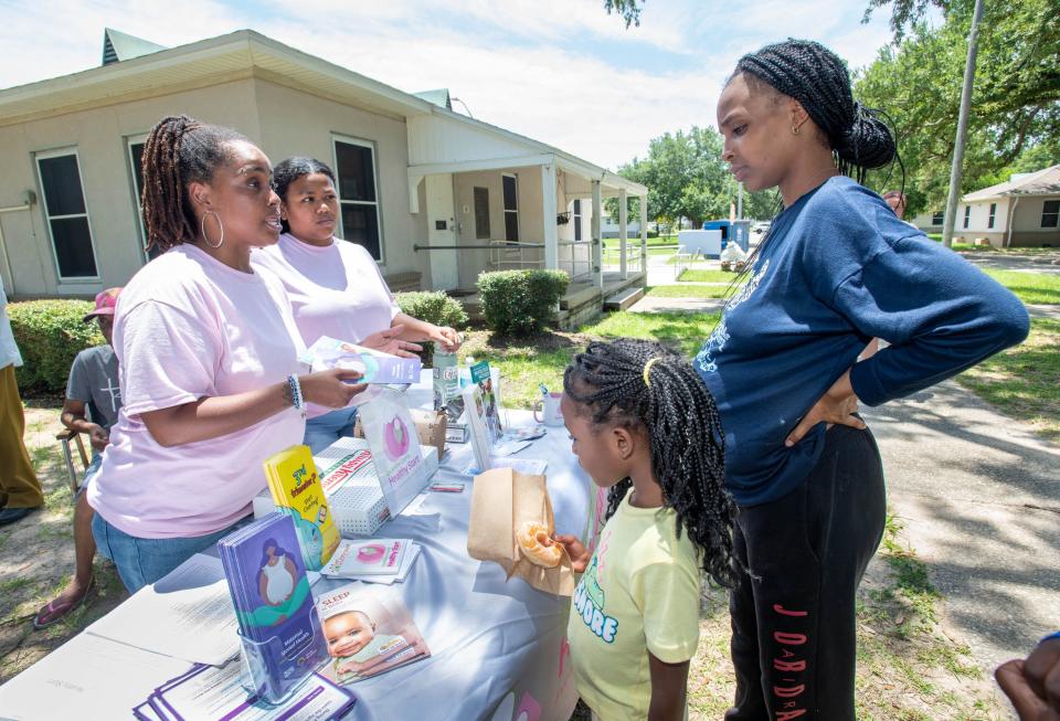 From left, Escambia County Healthy Start Coalition community liason Lakeila Robertson and projects coordinator Jade Christian talk with Cariel Cook, 6, and her mother Ariel Cook during an outreach event at Attucks Court in Pensacola on Monday, June 26, 2023.
