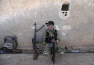 A Turkey-backed Syrian rebel fighter sits with his weapon near the border town of Tel Abyad