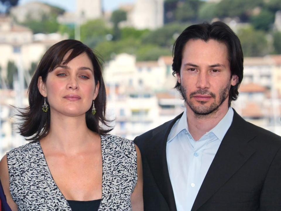 Keanu Reeves and Carrie-Anne Moss at a photocall for ‘The Matrix Reloaded’ at the Cannes Film Festival on 15 May 2003 (FRANCOIS GUILLOT/AFP via Getty Images)