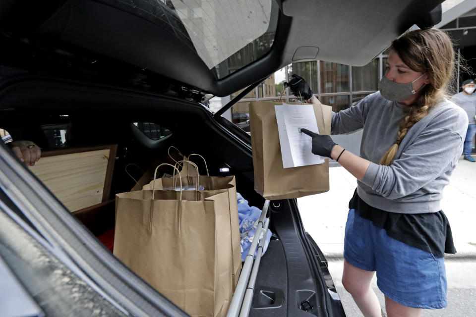 Marry Hammell, a staffer from Alinea restaurant, places carryout orders in the trunk of a car for a customer in Chicago, Saturday, June 20, 2020. Due to the coronavirus Alinea shifted to carryout on March 17. Since then, it has served 82,000 meals, said Nick Kokonas, the restaurant's co-owner. (AP Photo/Nam Y. Huh)