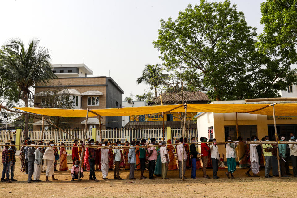 Voters stand in a queue to cast their votes outside a polling booth during first phase of elections in West Bengal state in Medinipur, India, Saturday, March 27, 2021. Voting began Saturday in two key Indian states with sizeable minority Muslim populations posing a tough test for Prime Minister Narendra Modi’s popularity amid a months-long farmers’ protest and the economy plunging with millions of people losing jobs because of the coronavirus pandemic. (AP Photo/Bikas Das)