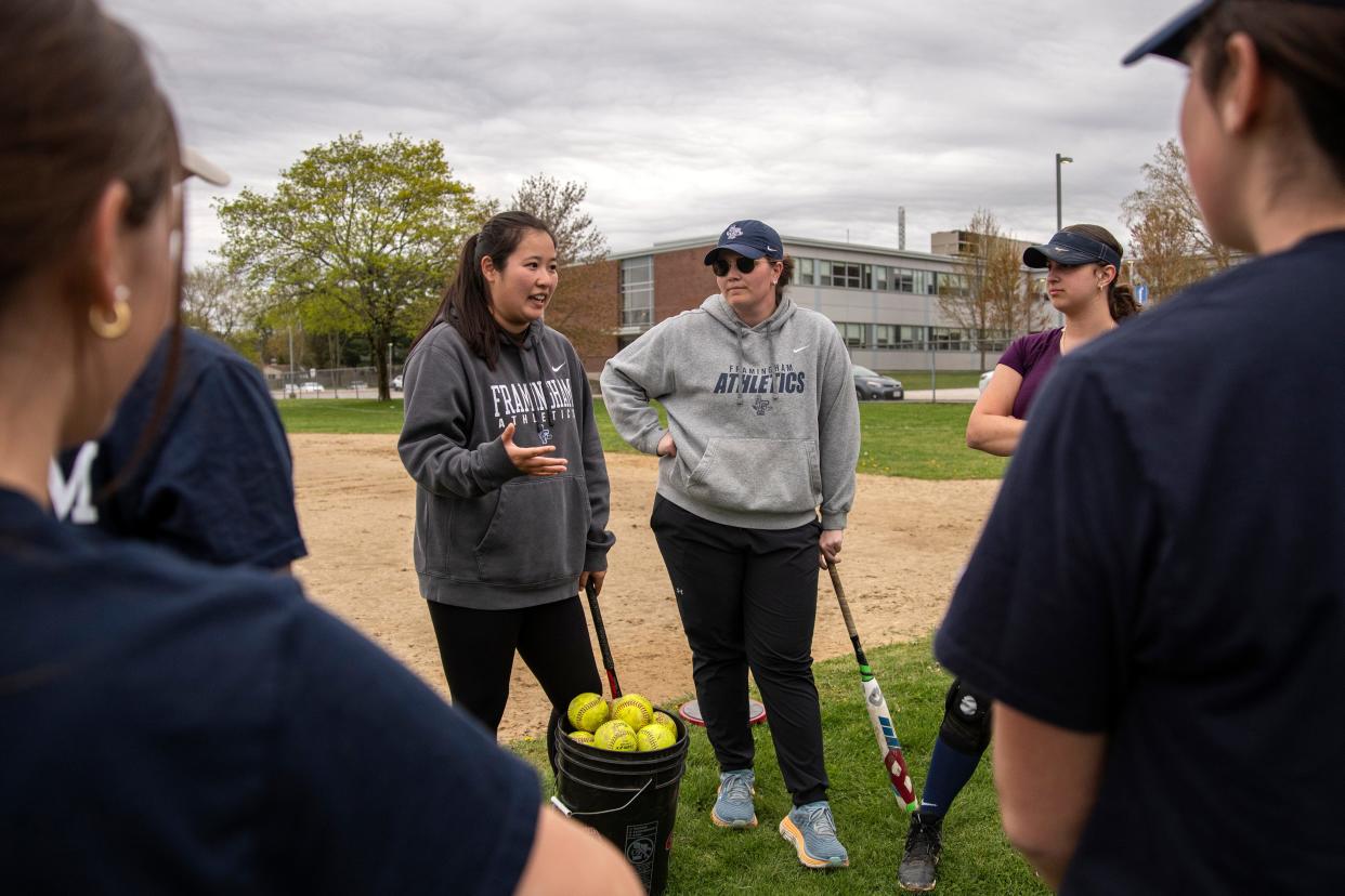 Framingham varsity softball head coach Kaitlyn Seeto (left) and assistant coach Jill Jones, both 2017 FHS graduates, talk with the team during varsity softball practice at Framingham High School, April 30, 2024.