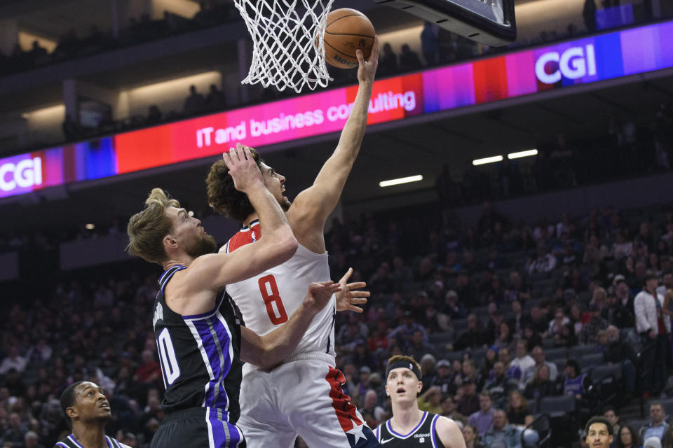 Washington Wizards forward Deni Avdija (8) lays up the ball over Sacramento Kings forward Domantas Sabonis (10) during the first quarter of an NBA basketball game in Sacramento, Calif., Monday, Dec. 18, 2023. (AP Photo/Randall Benton)