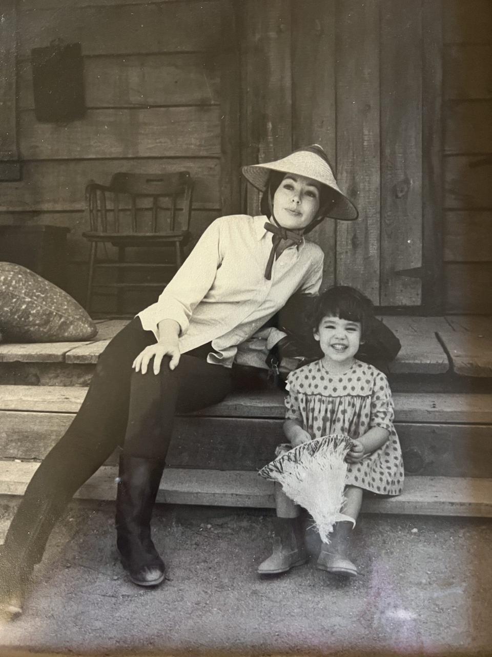 An old picture of Barbara Rush and her daughter sitting on a set of stairs.