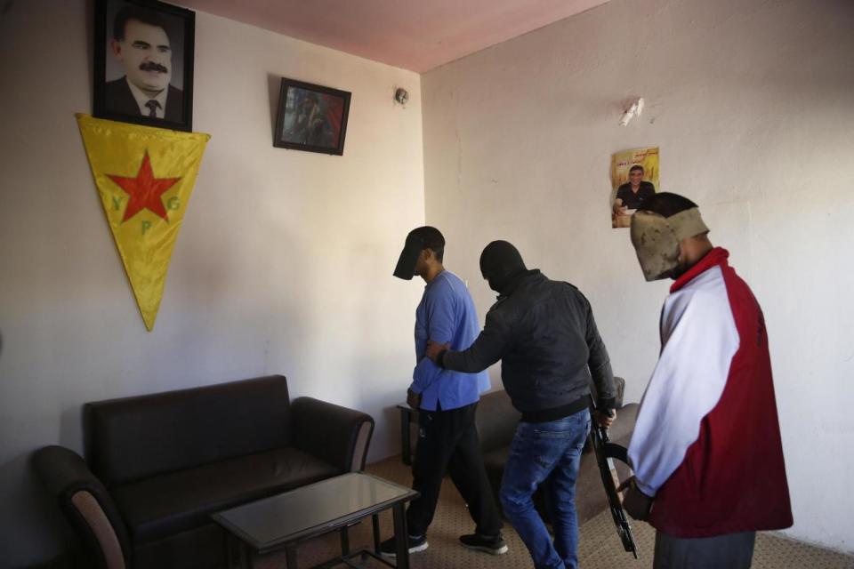 A Kurdish security officer, center, walks Alexanda Amon Kotey, left, and El Shafee Elsheikh to seats for a media interview (AP)