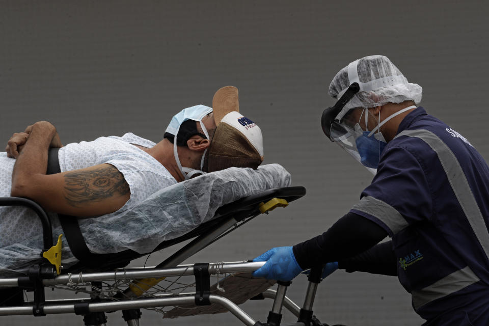 A healthcare worker transfers a patient suspected of having COVID-19 from an ambulance into the HRAN public hospital in Brasilia, Brazil, Thursday, April 29, 2021. (AP Photo/Eraldo Peres)