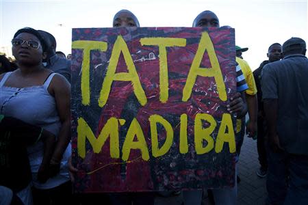 People hold a poster reading "Tata Madiba" as they take part in an interfaith service for former President Nelson Mandela held in front of the Town Hall on Grand Parade in Cape Town December 6, 2013. REUTERS/Mark Wessels