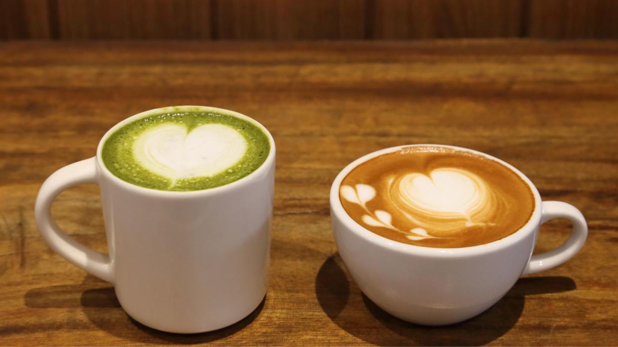  Matcha vs coffee - a matcha latte next to a latte on a wooden table. 