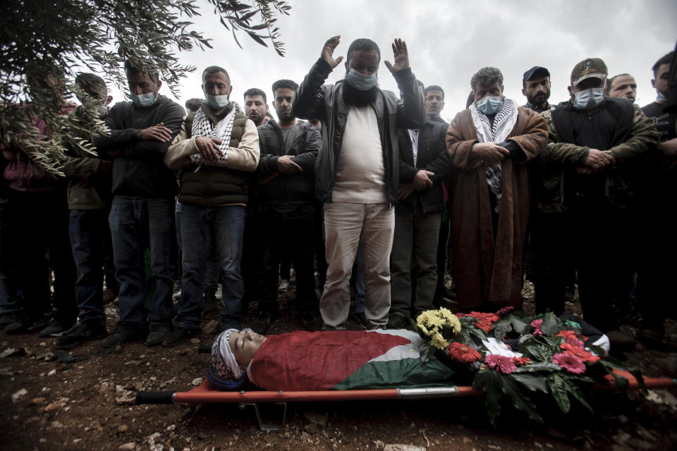 Relatives mourn the body of a 13-year-old Ali Abu Alia who was shot dead by Israeli military forces during clashes with a stone-throwing Palestinains during his funeral in al-Mughair village near the West Bank city of Ramallah, Saturday, Dec. 5, 2020. (AP Photo/Majdi Mohammed)